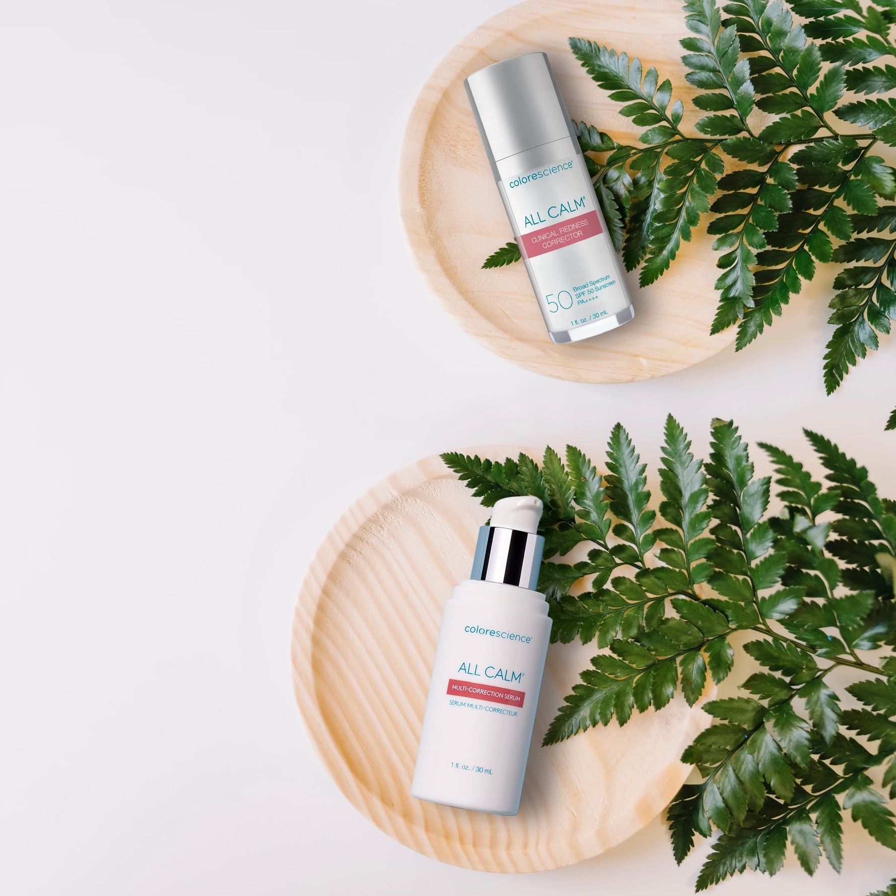 Two skincare bottles labeled 'All Calm' on wooden plates with green leaves.