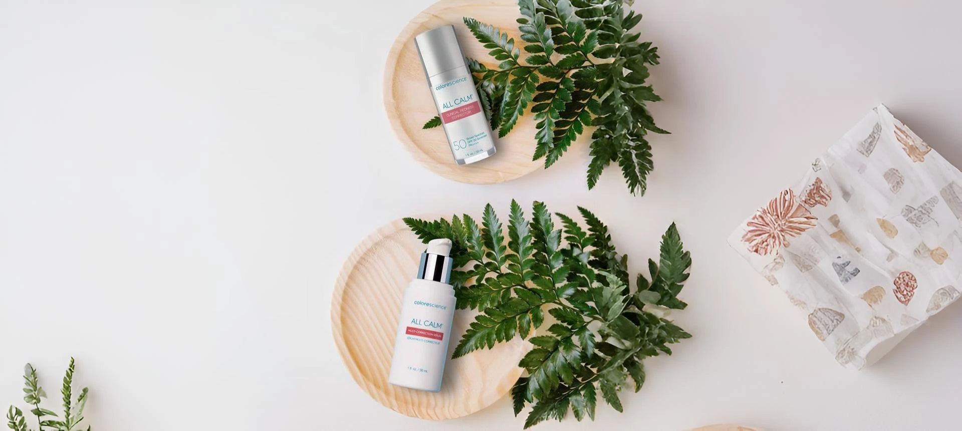 Cosmetic bottles on wooden trays with fern leaves on a light background